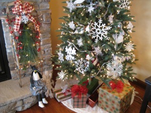 In my living room, a snowflake tree lives next to the fire place.  I have a pair of old ice skates shoved in the center and various sizes of snowflakes and snow images.  An old sled and Mr. Penguin complete the scene.  
