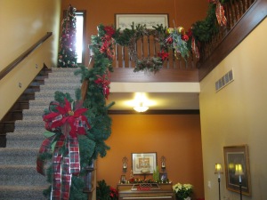 The foyer is decorated with garland, poinsettia flowers, and plaid ribbon.
