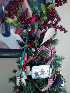 The topper for the kitchen tree includes holly stems, wooden spoons and a spatula.  I used torn gingham fabric for the garland.  